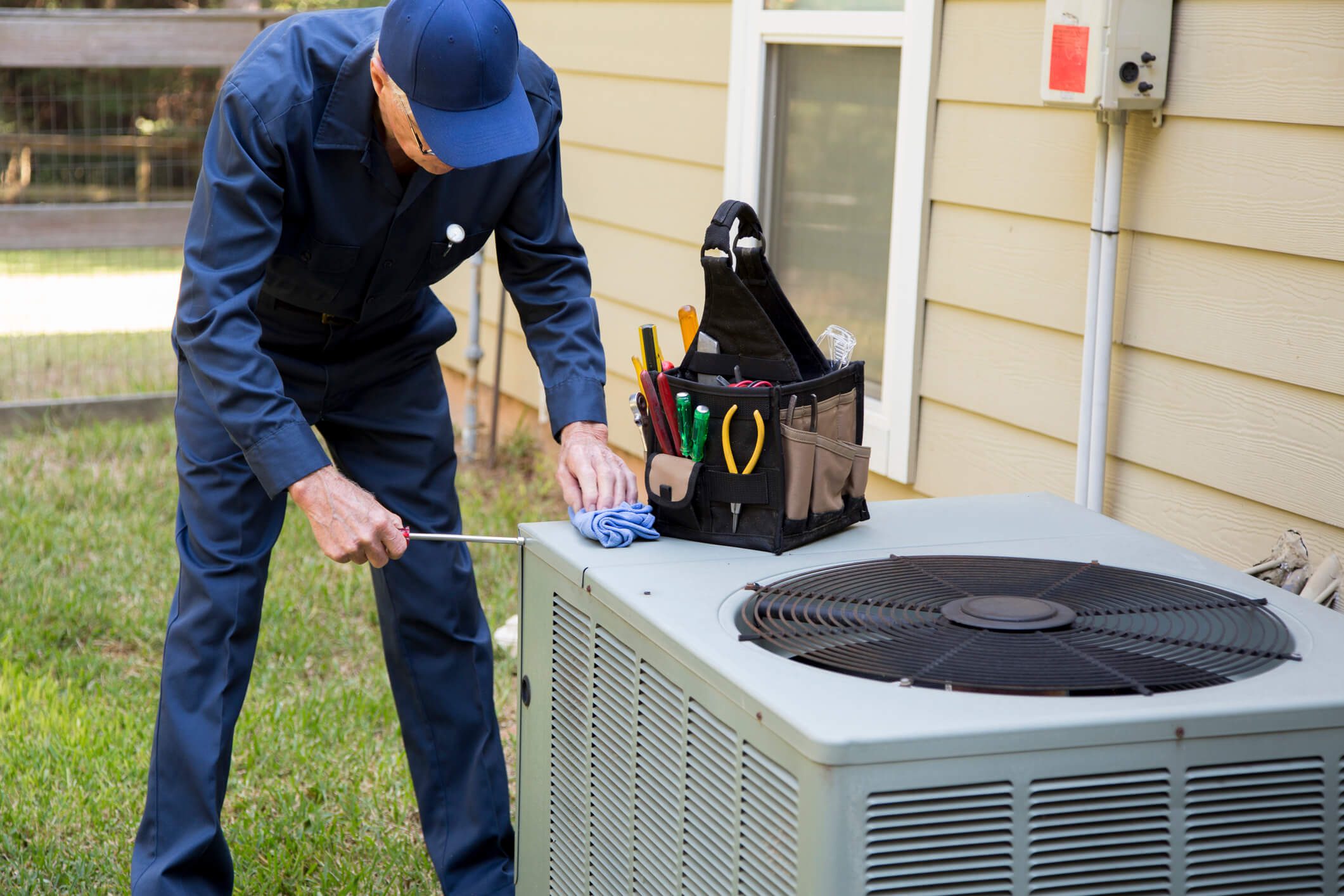 Technician repairing outdoor air conditioning unit.