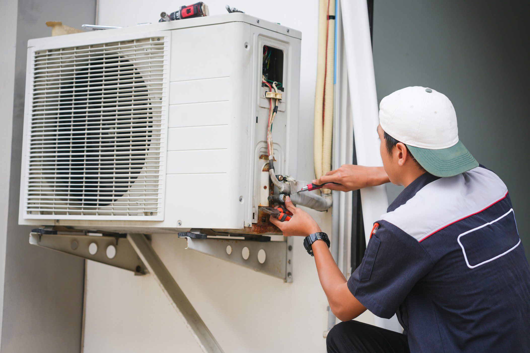 Technician repairing outdoor air conditioning unit