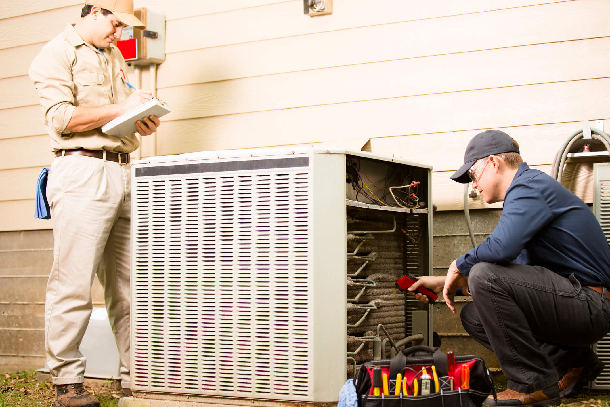 Technicians inspecting outdoor HVAC unit together.