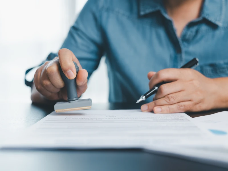 Person signing and stamping a paper
