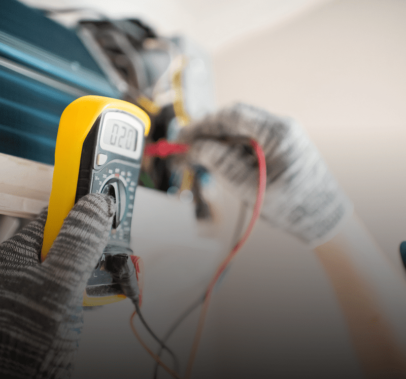 Technician using multimeter on air conditioner