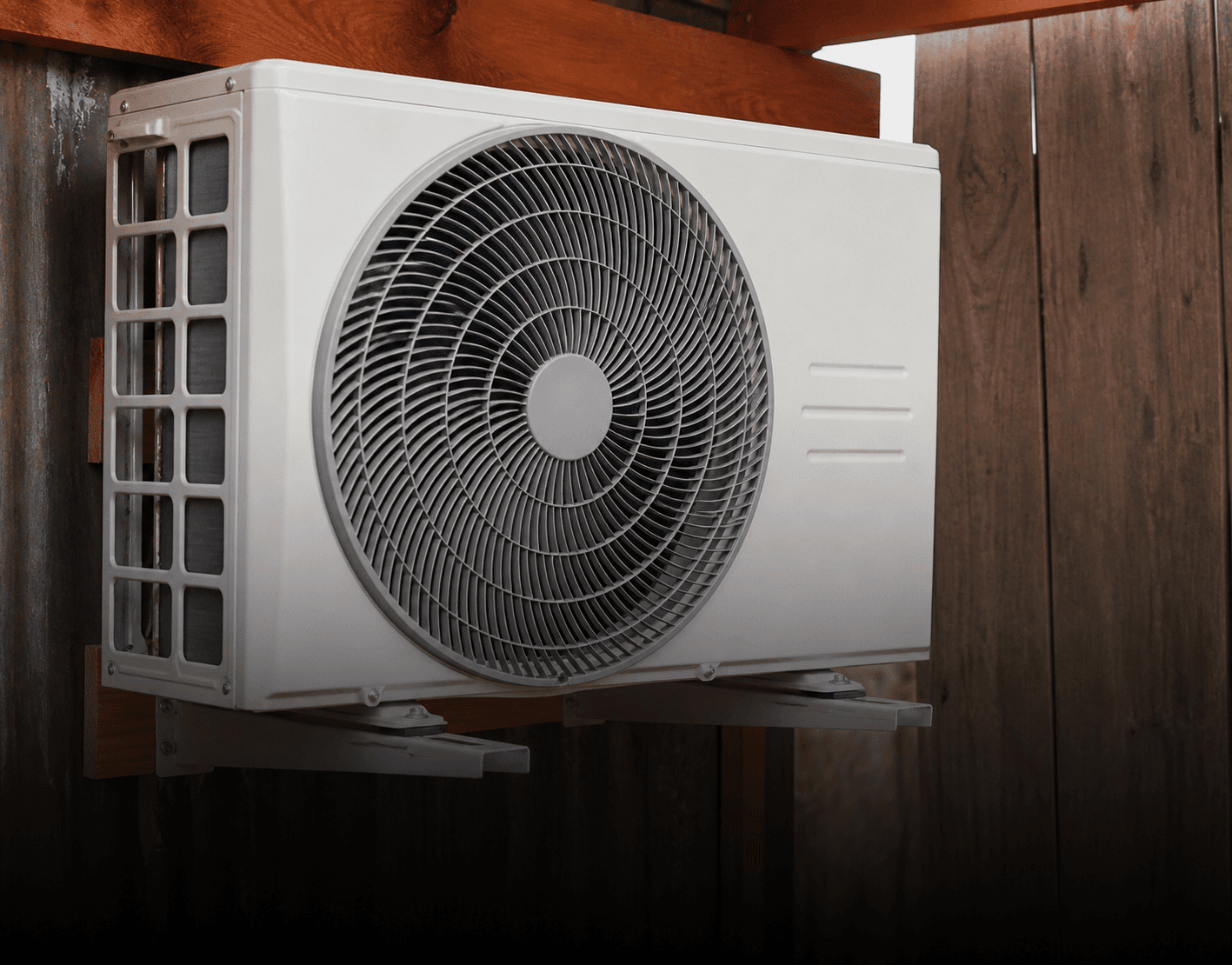 Outdoor air conditioning unit on wooden wall.